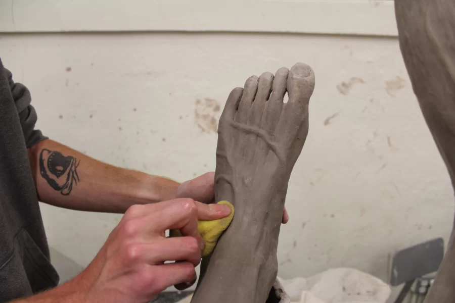 Halverson uses a sponge to help shape the veins around the foot of his creation. It is important to move slowly and smoothly to avoid making a mistake. PHOTO / CONNOR CREEDON