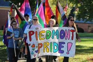 Biology Professor Julia Schmitz (left), former student Max Daves, and head of student support services Ineke Dyer (right) carrying the "Piedmont Pride" sign to the quad during the pride walk.